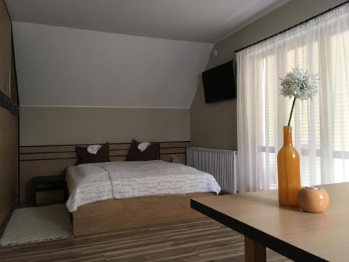 een slaapkamer met een bed en een vaas met bloemen erin bij Sétány Apartman in Csopak