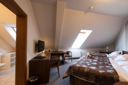 a hotel room with a bed and a desk with a computer at Hotel Mario in Lednice