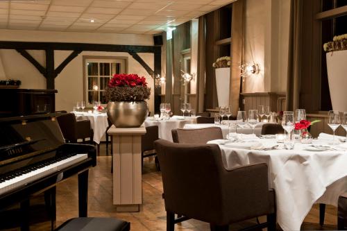 a restaurant with white tables and a piano at De Klomp Charme Hotel & Restaurant in Vilsteren