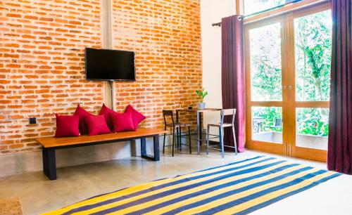 a room with a bench with red pillows and a brick wall at Roshara Nalla in Giriulla