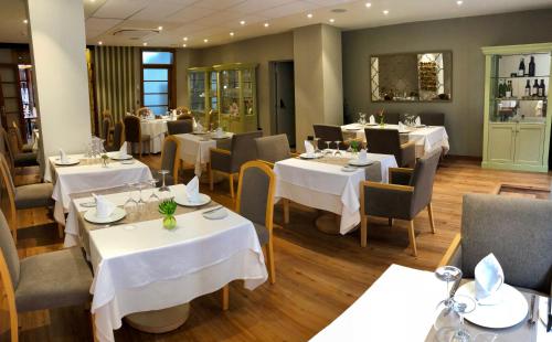 a restaurant with tables and chairs with white tablecloths at Laguna Nivaria Hotel & Spa in La Laguna