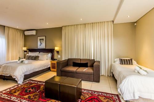 a hotel room with two beds and a couch at Lemoenkloof Boutique Hotel in Paarl