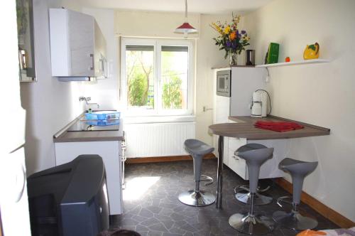 uma cozinha com um balcão, uma mesa e bancos em Chez Joséphine em Saarbrücken