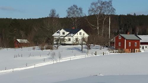 ein schneebedecktes Feld mit Häusern und einer roten Scheune in der Unterkunft The Sheep Inn B&B in Arvika