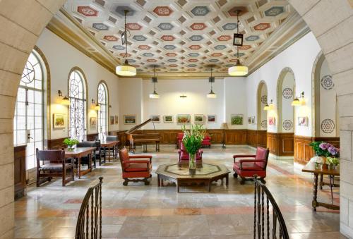 a lobby with tables and chairs and a piano at YMCA Three Arches Hotel in Jerusalem