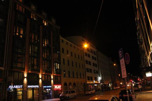a city street at night with buildings and cars at ARABEST Aparthotel & Boardinghouse in Munich