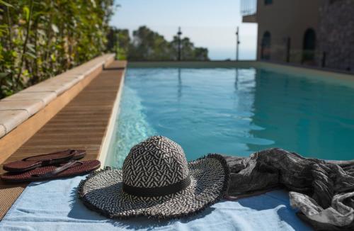 a hat and flip flops next to a swimming pool at Hotel Villa Ducale in Taormina