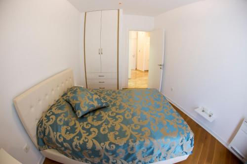 a bedroom with a bed with a blue and gold blanket at Apartman Anna Tre Canne Budva in Budva