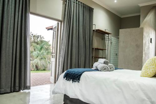 a bedroom with a bed and a large window at Blue Rain Guest House in Bloemfontein