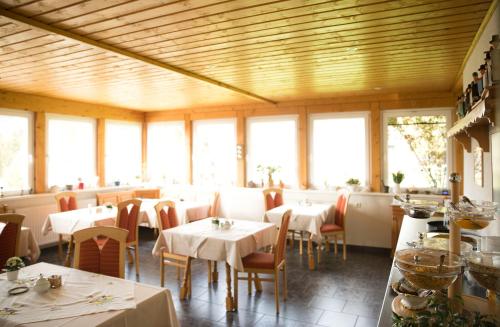 a dining room with tables and chairs and windows at Landhaus Fischer in Sankt Andreasberg