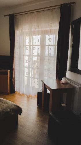 a room with a bed and a table and a window at Pensiunea Codruta in Carpinis