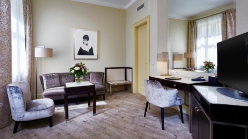 a hotel room with a desk and chairs and a living room at Aria Hotel Prague in Prague