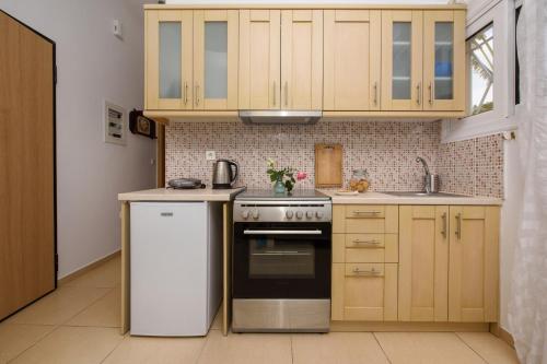 a kitchen with wooden cabinets and a stove top oven at Romantic Palace Beach Apartments in Agios Gordios