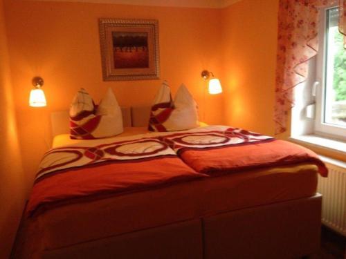a bedroom with a bed with orange walls and a window at Ferienhaeuser-Am-Eichenberg-Haus-2 in Blankenburg
