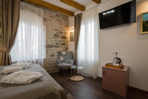 a bedroom with two beds and a tv on the wall at ID Regal Residence in Split