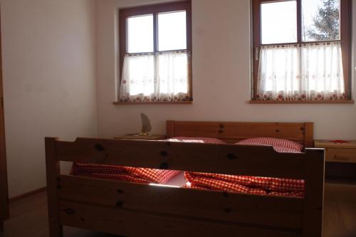 a bedroom with two windows and a bed with red pillows at Le Maier in San Vigilio Di Marebbe
