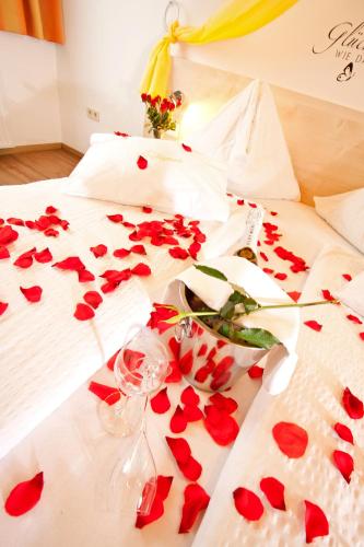 a bed with red roses on it with a bunch of hearts at Gasthof Spengerwirt in Hirschegg Rein