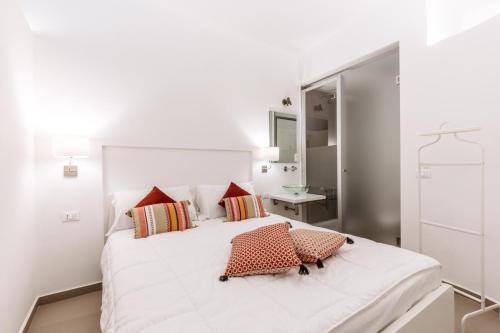 a white bedroom with a large white bed with red pillows at Loft Piazza Marina by DomuSicily in Palermo