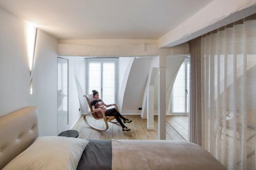 une femme assise sur une chaise dans une chambre dans l'établissement Opera Lieu Unique, à Paris