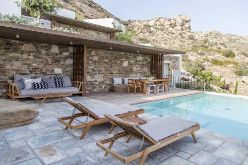 un patio con tavolo, sedie e piscina. di Hide Out Suites a Mylopotas