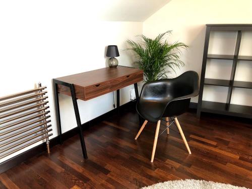 a black chair sitting next to a desk with a plant at Arkada Wadowice in Wadowice