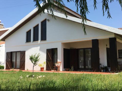 a white house with black windows and a yard at Happy Ria House in Gafanha da Nazaré