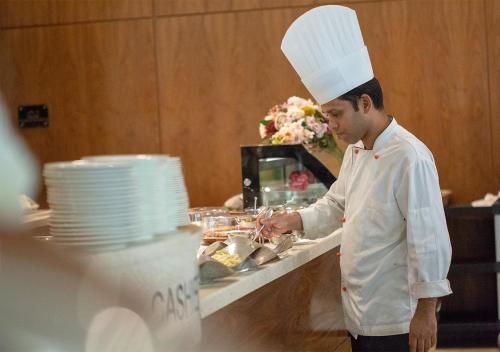 a man in a chefs hat preparing food in a kitchen at Holiday Suites Al Azizia in Makkah