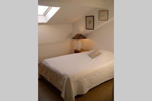 ein Schlafzimmer mit einem weißen Bett und einem Fenster in der Unterkunft Les Palatines Penthouse in Saint-Raphaël
