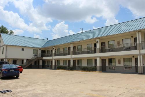 a large building with a car parked in a parking lot at Scottish Inns Westcott Street in Houston