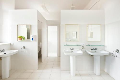 a white bathroom with two sinks and mirrors at Alberg Solidança Hostel in Palafrugell