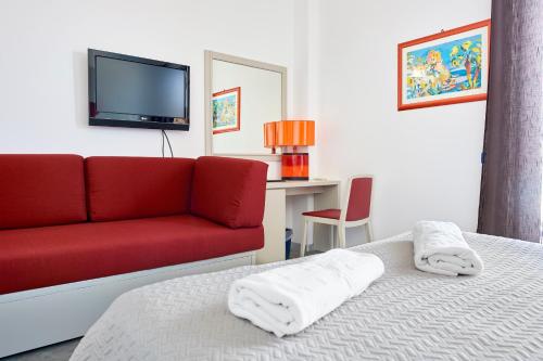 a bedroom with a bed and a red couch at Hotel La Battigia in Alcamo Marina