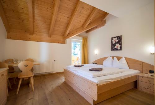 ein Schlafzimmer mit einem großen Bett und einer Holzdecke in der Unterkunft Hotel Alpin in Gossensaß