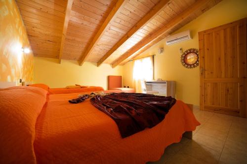 a bedroom with an orange bed with a wooden ceiling at B&B Il Nido in SantʼAntìoco
