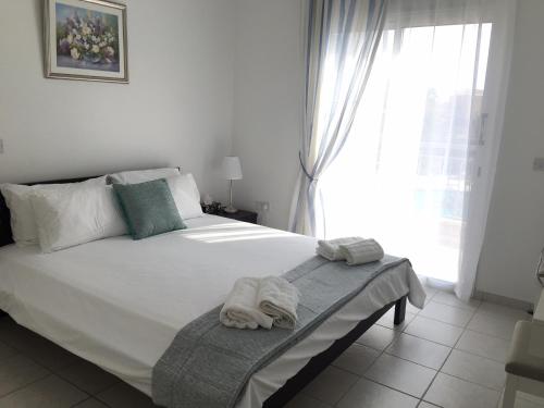 sypialnia z białym łóżkiem i ręcznikami w obiekcie Modern pool facing apartment in popular Limnaria Gardens w Pafos