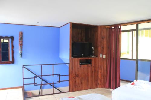 a room with a tv and a blue wall at La Posada Jungle Hotel in Manuel Antonio