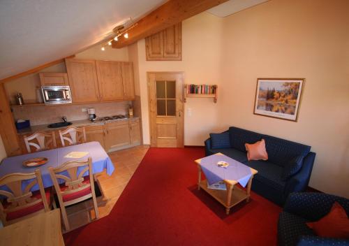 a living room with a couch and a table and a kitchen at Ferienwohnungen am Kurpark in Roßhaupten