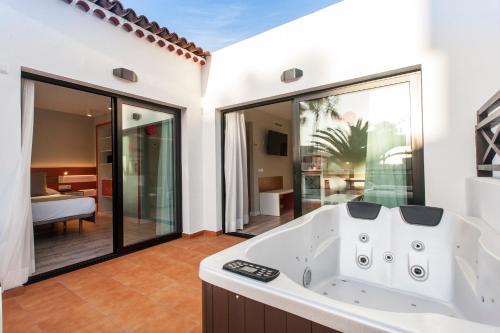 a bathroom with a tub and a bedroom at Vanilla Garden Boutique Hotel - Adults Only in Playa de las Americas
