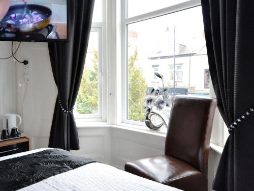 a bedroom with a bed and a chair and a window at South Shore Guest House in South Shields