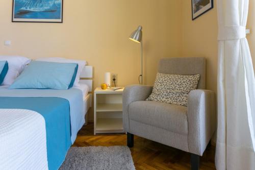 a bedroom with a bed and a chair and a lamp at Villa Benic in Dubrovnik