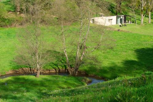 a small river in a grassy field with a house at La grange des Palles in Vijon