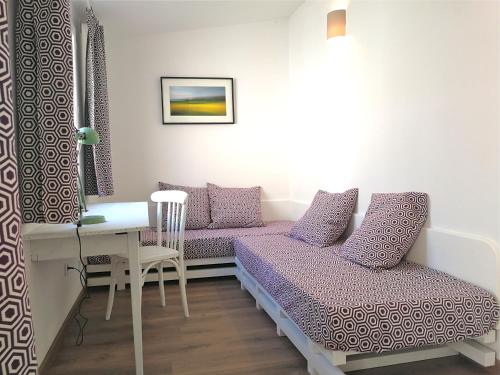 une chambre avec deux lits, une table et un bureau dans l'établissement Un jardin sur le toit - Saintes, à Saintes