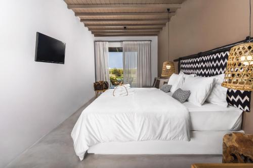 a bedroom with a large white bed and a window at My Mykonos Hotel in Mýkonos City
