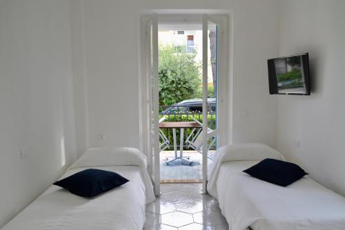 two beds in a room with a door to a patio at Case Vacanze Ganimede in Sperlonga