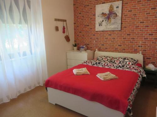 a bedroom with a bed with red sheets and a brick wall at Apartment Lucia in Sveti Križ Začretje