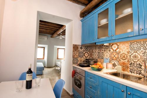 a kitchen with blue cabinets and a table with a bottle of wine at Gavrion's Nest - Premium Cycladic Studio in Gavrion