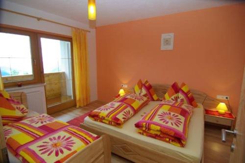 um quarto com 2 camas e almofadas coloridas em Landhaus Oberlehen em Rohrberg