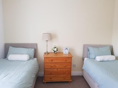 a bedroom with two beds and a dresser with a lamp at Georgian 8 bed, 4 room, home from home in Derry Londonderry