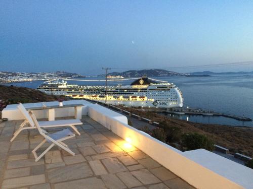 a cruise ship docked in a harbor with a chair at Sea Wind Apartments in Agios Stefanos
