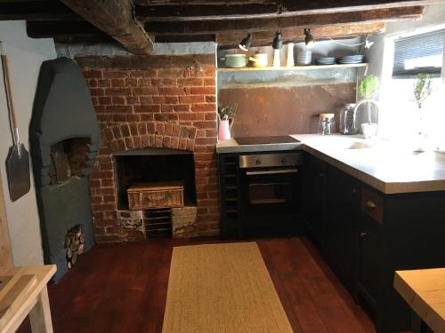 a kitchen with a brick oven and a brick fireplace at Watt Cottage in Ipswich
