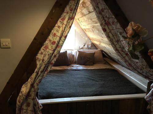 a bed with a canopy in a room with a window at Watt Cottage in Ipswich